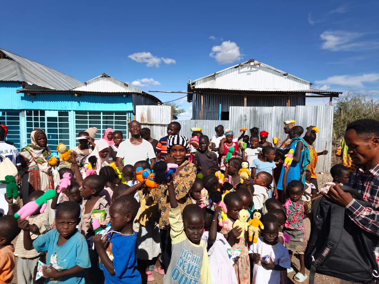 Children holding handmade dolls at a community distribution day